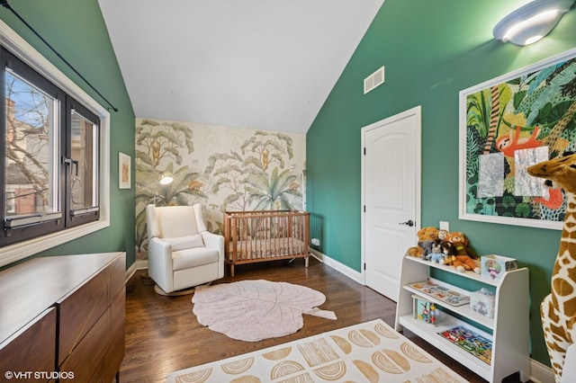 sitting room featuring wood finished floors, visible vents, baseboards, vaulted ceiling, and an accent wall