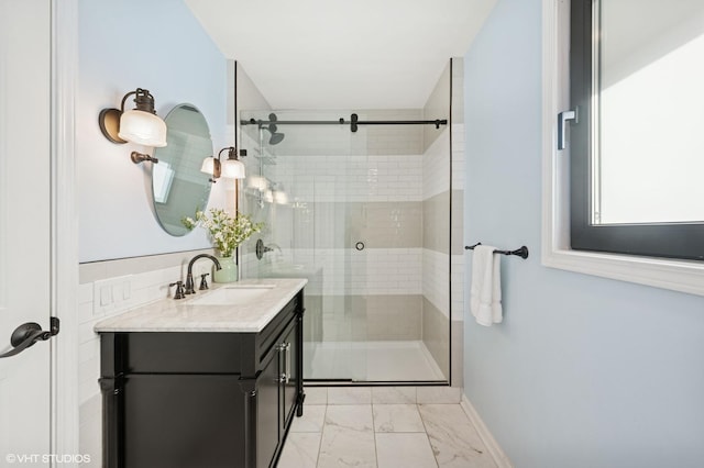 bathroom featuring marble finish floor, vanity, a shower stall, and baseboards