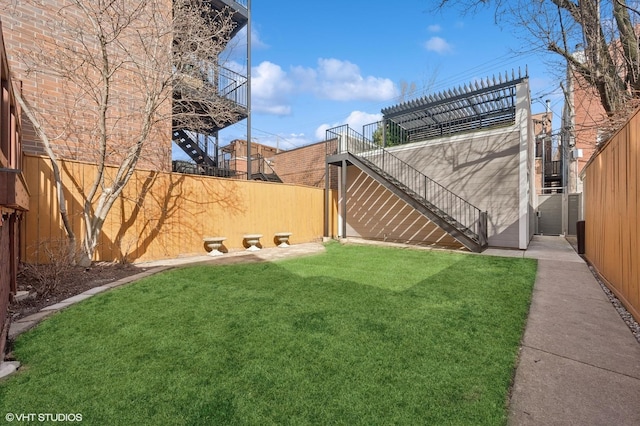 view of yard featuring a fenced backyard and stairs