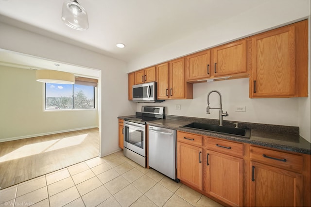 kitchen with light tile patterned floors, recessed lighting, appliances with stainless steel finishes, brown cabinetry, and a sink