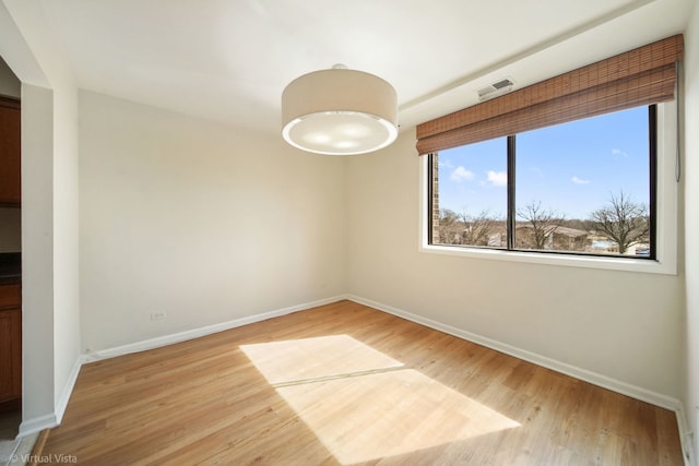 empty room with visible vents, baseboards, and wood finished floors