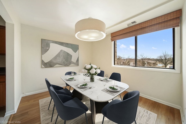 dining room featuring visible vents, baseboards, and wood finished floors