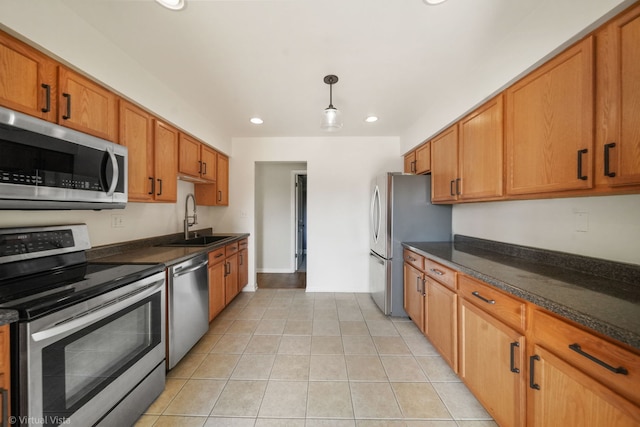 kitchen with light tile patterned floors, recessed lighting, brown cabinets, appliances with stainless steel finishes, and a sink