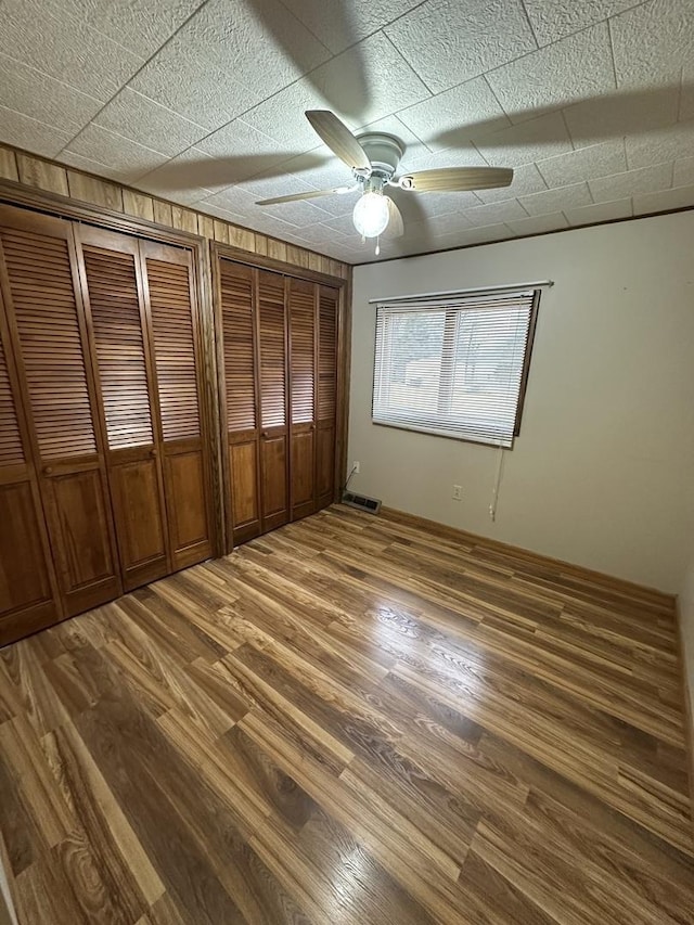 unfurnished bedroom with visible vents, wood finished floors, and a ceiling fan