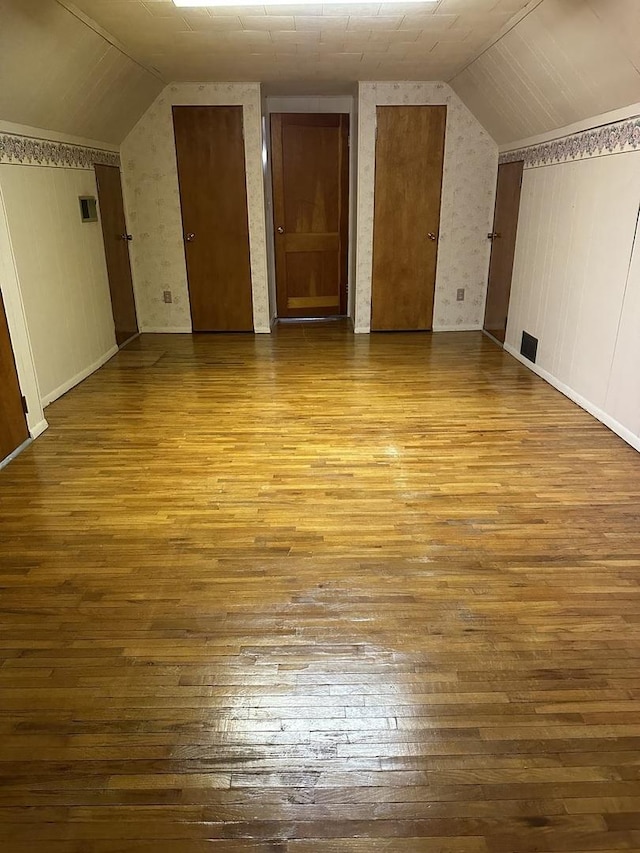 additional living space featuring visible vents, vaulted ceiling, and hardwood / wood-style floors