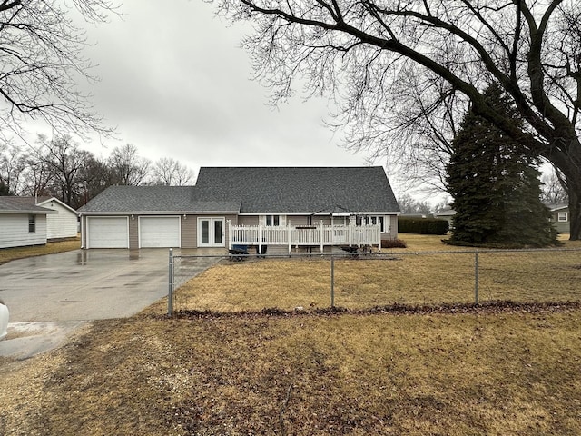 view of front facade featuring roof with shingles, an attached garage, a front yard, fence, and driveway