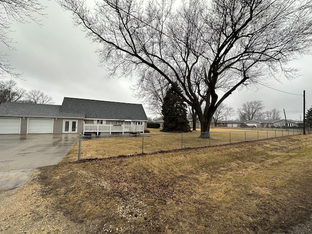 view of front facade featuring an attached garage, driveway, fence, and a front yard