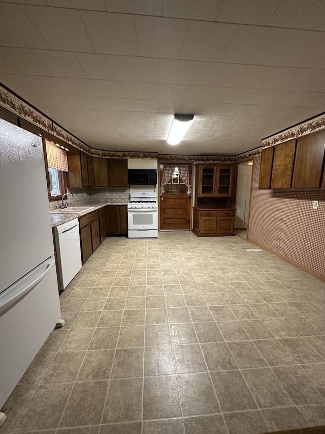 kitchen with white appliances, a sink, light countertops, range hood, and wallpapered walls