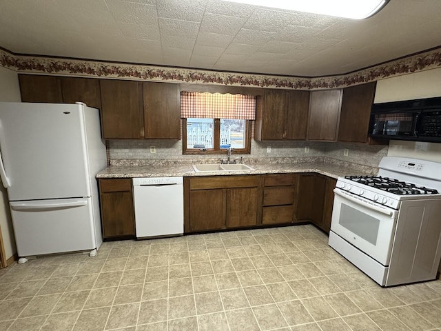 kitchen featuring dark brown cabinets, white appliances, backsplash, and a sink