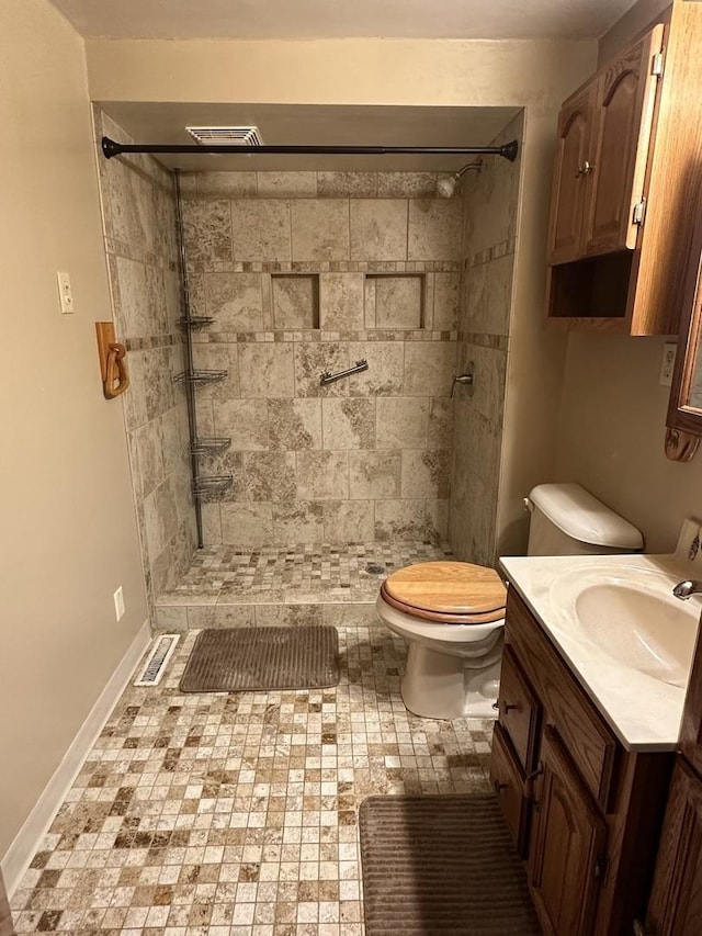 full bathroom with toilet, visible vents, vanity, baseboards, and a tile shower