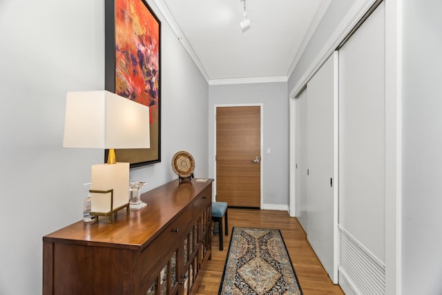 entryway with track lighting, wood finished floors, and crown molding