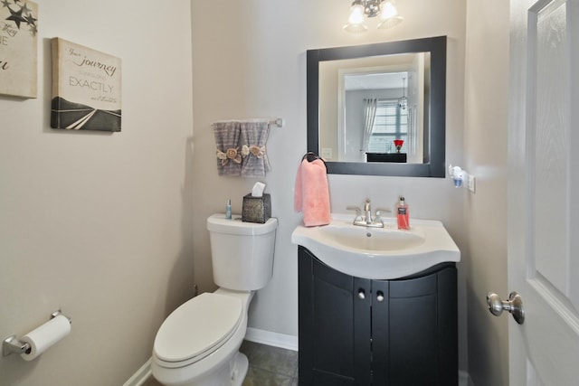 bathroom with tile patterned flooring, baseboards, vanity, and toilet