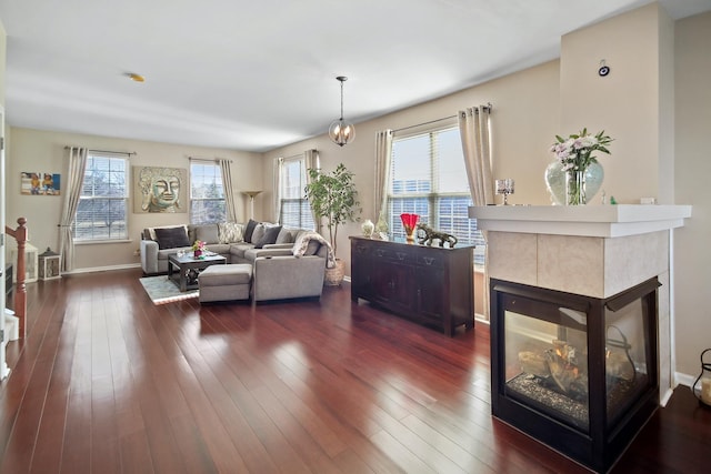 living area featuring dark wood-type flooring, a fireplace, and baseboards