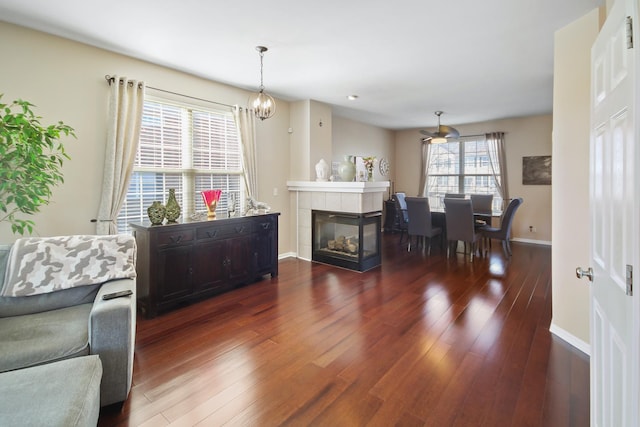 living room with a chandelier, a tile fireplace, hardwood / wood-style flooring, and baseboards