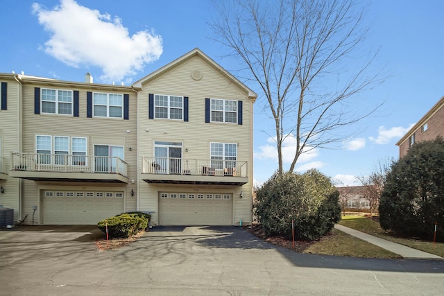 multi unit property featuring a garage, cooling unit, and driveway