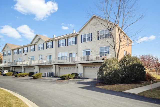 view of property with a garage, driveway, central AC unit, and a residential view