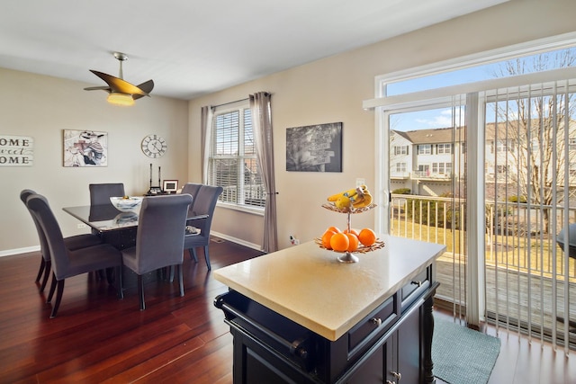 dining area with dark wood-style floors, ceiling fan, and baseboards