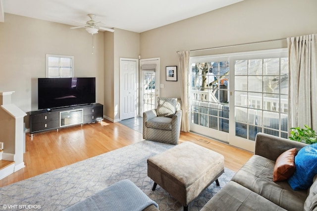 living room featuring ceiling fan, visible vents, baseboards, and wood finished floors