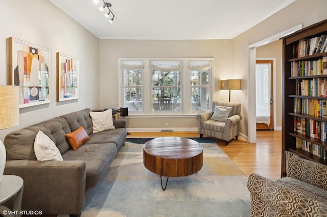 living area with rail lighting, baseboards, wood finished floors, and crown molding