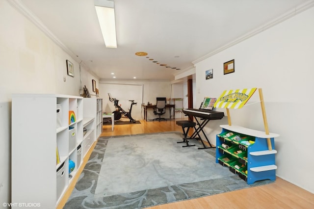 recreation room featuring wood finished floors and ornamental molding