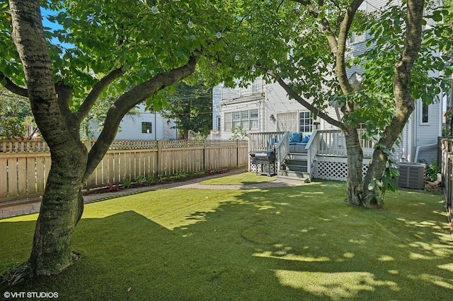 view of yard with a deck, a fenced backyard, and central AC