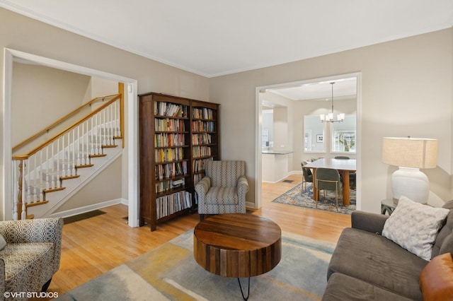 living area with stairway, wood finished floors, baseboards, and ornamental molding