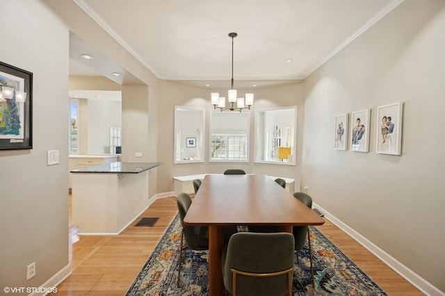 dining area with crown molding, baseboards, visible vents, and light wood finished floors