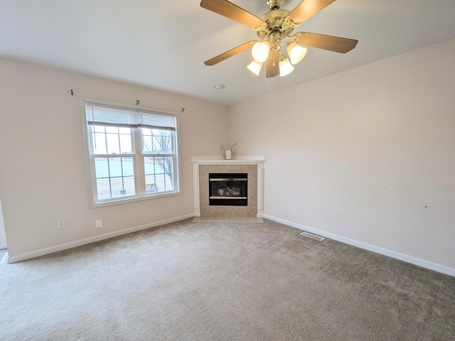 unfurnished living room featuring visible vents, baseboards, a ceiling fan, a tiled fireplace, and carpet