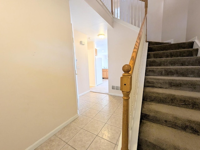 stairway with visible vents, baseboards, and tile patterned floors