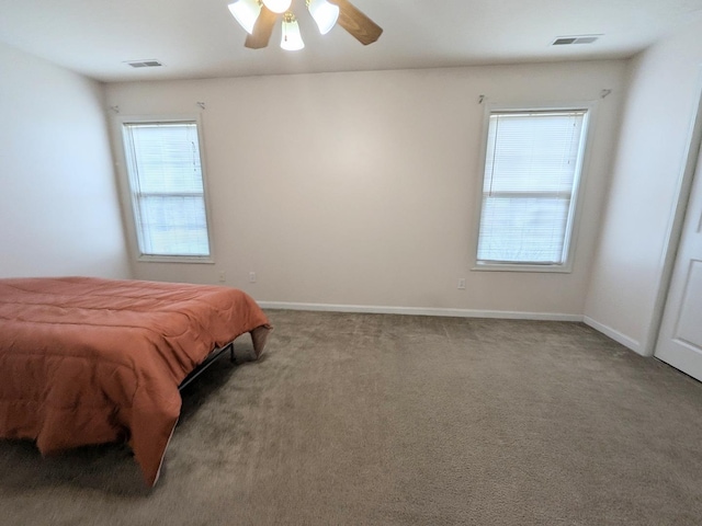 carpeted bedroom featuring a ceiling fan, visible vents, and baseboards