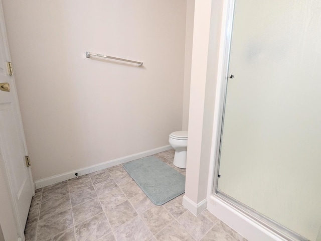 full bathroom with a stall shower, toilet, and baseboards