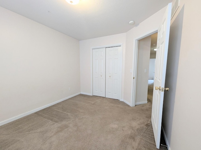 unfurnished bedroom featuring carpet floors, baseboards, and a closet