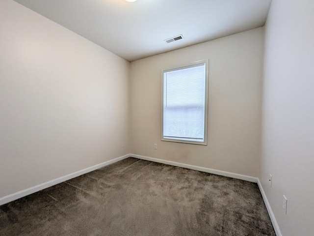 unfurnished room featuring visible vents, dark carpet, and baseboards