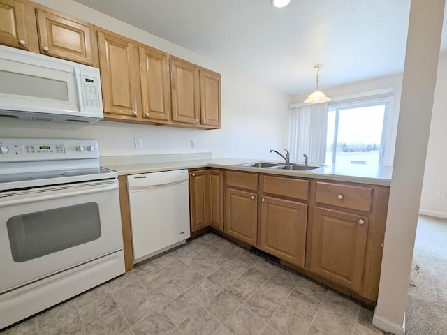 kitchen with a peninsula, white appliances, a sink, light countertops, and decorative light fixtures