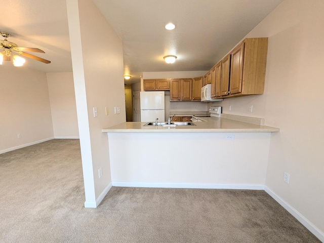 kitchen featuring light countertops, light colored carpet, a sink, white appliances, and a peninsula