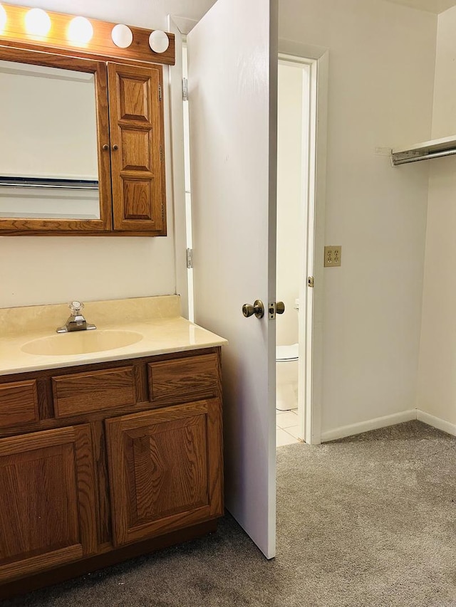 bathroom with toilet, baseboards, and vanity