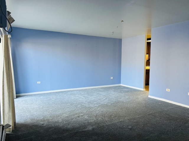 carpeted empty room featuring baseboards