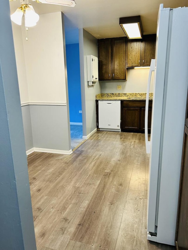 kitchen featuring light wood-style flooring, dark brown cabinetry, white appliances, baseboards, and light countertops