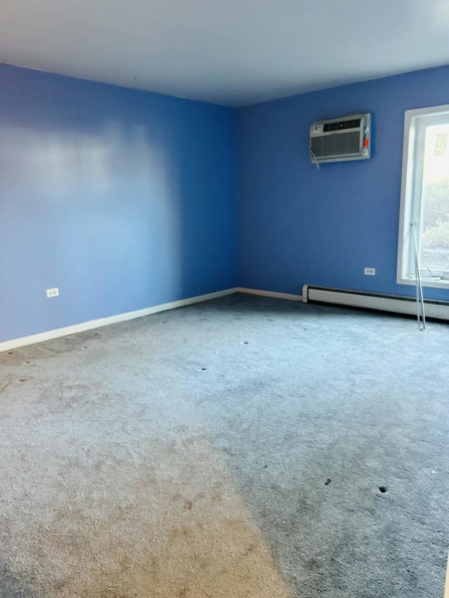 unfurnished room featuring a baseboard heating unit, carpet, a wall mounted air conditioner, and baseboards