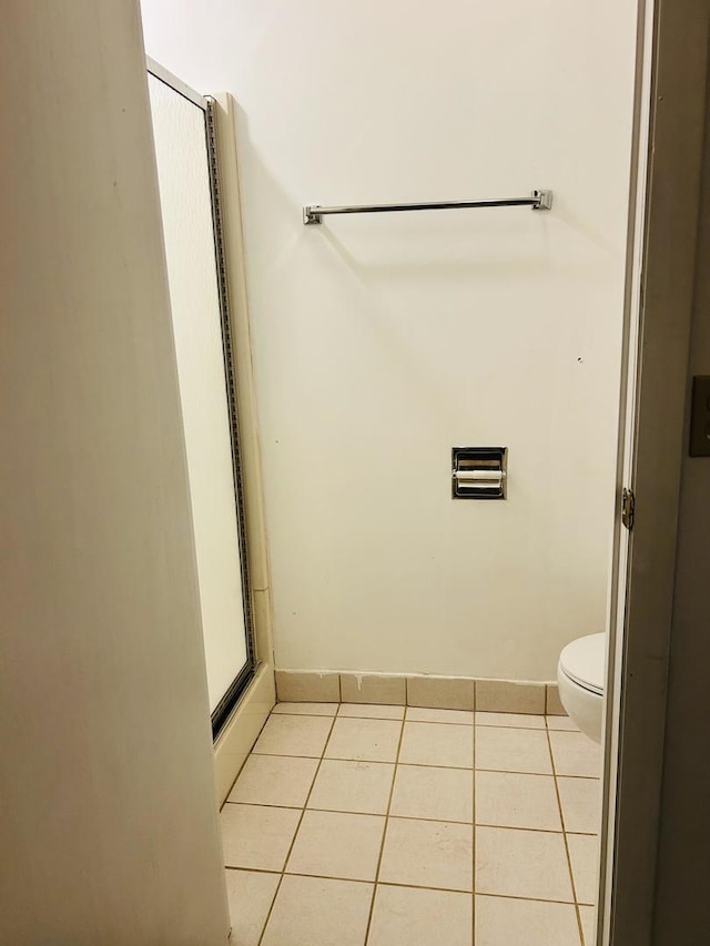 bathroom with tile patterned flooring, baseboards, and toilet