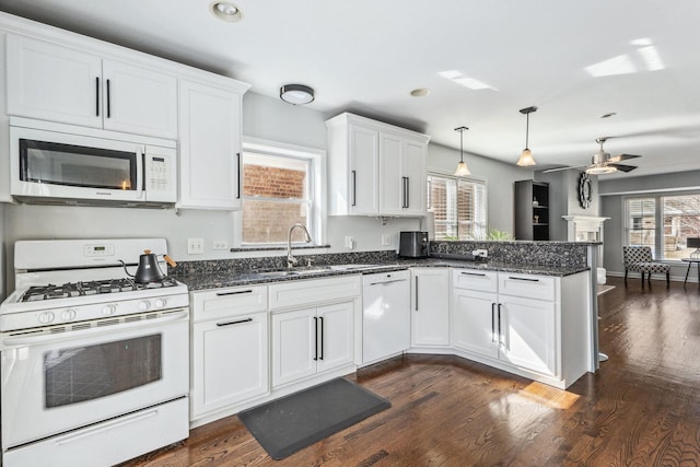 kitchen featuring a sink, dark stone countertops, white appliances, a peninsula, and white cabinets