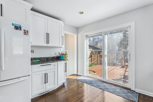 kitchen featuring dark wood finished floors, visible vents, white cabinets, and freestanding refrigerator