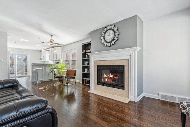 living area with a wealth of natural light, visible vents, dark wood-type flooring, and a high end fireplace