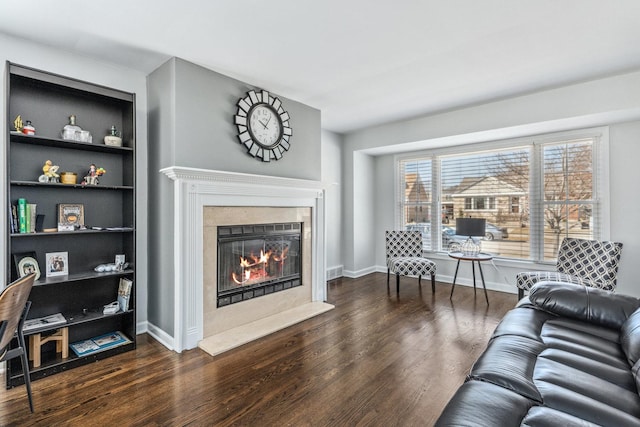 living room featuring built in shelves, baseboards, wood finished floors, and a high end fireplace