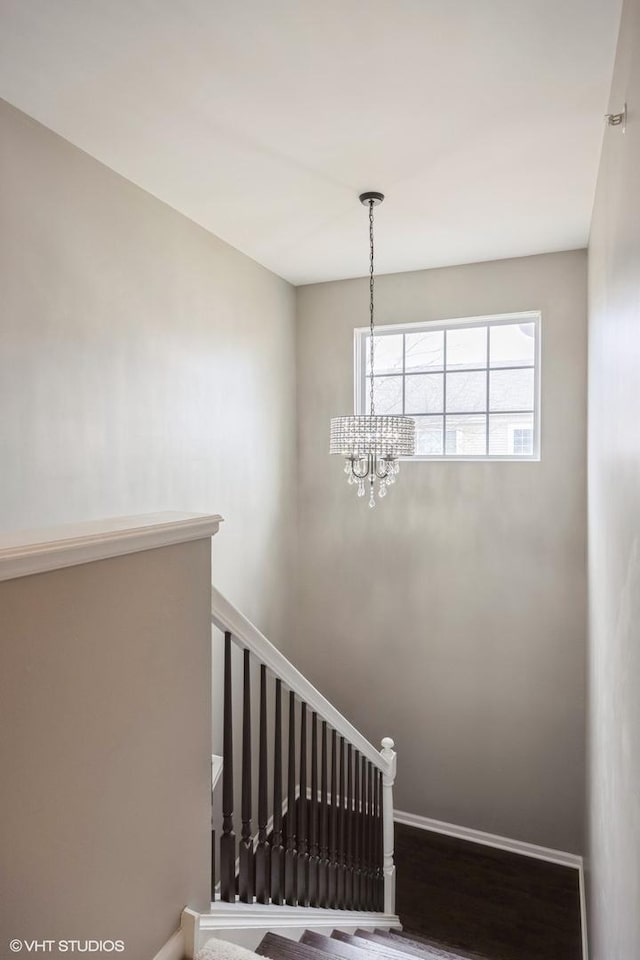 stairs with an inviting chandelier, baseboards, and wood finished floors