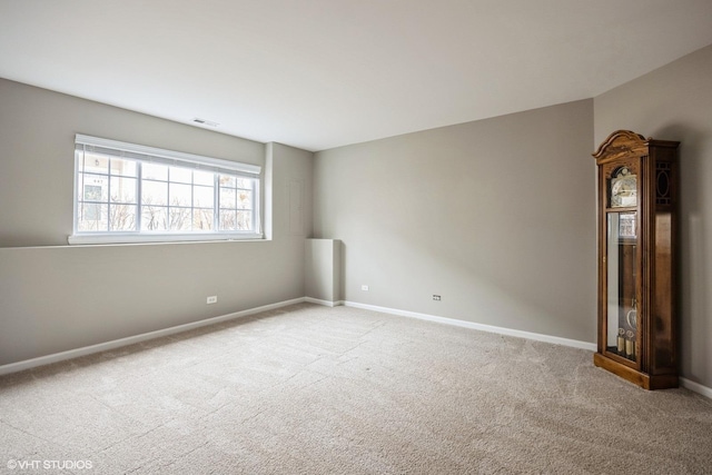 empty room featuring light carpet, visible vents, and baseboards