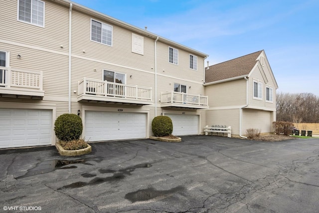 rear view of property featuring driveway and an attached garage