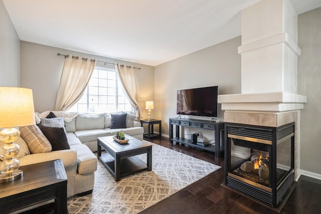 living room featuring baseboards, a tiled fireplace, and wood finished floors