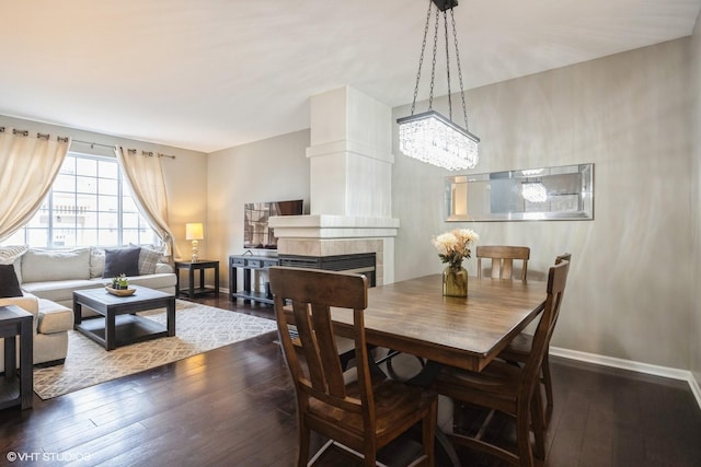 dining area featuring dark wood-style floors, a fireplace, and baseboards