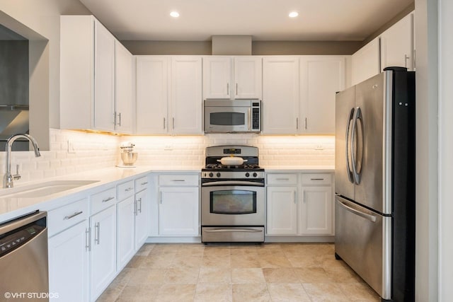 kitchen with white cabinets, stainless steel appliances, a sink, and light countertops